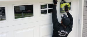 Featured image: Precision Door Service technician fixing a garage door. - Planning a Garage Door Franchise Investment: 3 Things to Consider