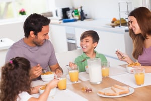 Family enjoying time together at the dinner table. - Take These 3 Steps Toward Work/Life Balance and Business Success