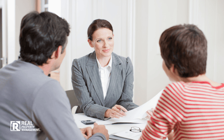 Woman with couple at desk at business meeting.