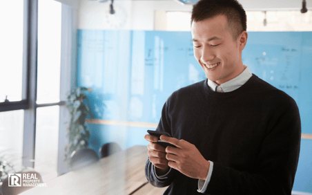 Man in business office looking at cellphone and smiling.