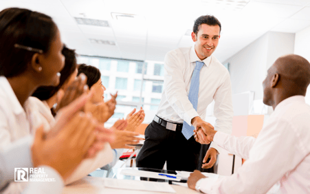 Business meeting with two men shaking hands and other people clapping