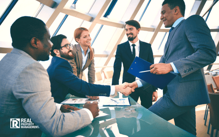 Several people dressed in business attire circled around a table Several people dressed in business attire circled around a table