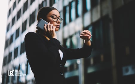 Franchise owner talking on phone and checking her watch in city setting