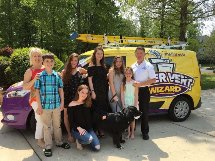 Family standing in front of a Dryer Vent Wizard van