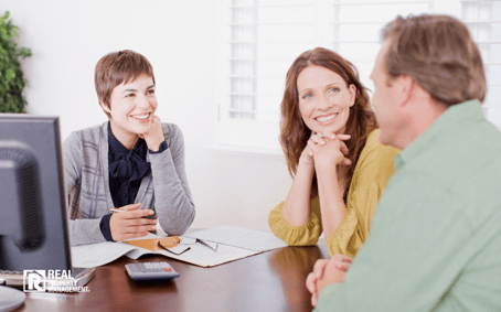 Woman talking to couple at real estate brokerage office