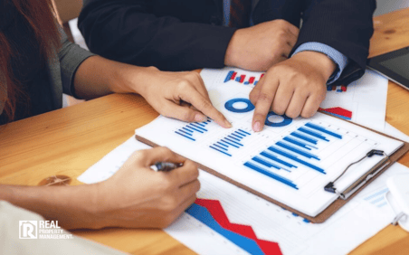 Two people looking at a revenue chart on a table Two people looking at a revenue chart on a table