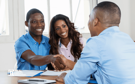 Property manager at desk shaking hands with couple