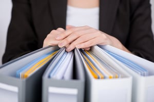 Organized binders with hands on top - Spring Cleaning: Organize Your Office for Maximum Productivity