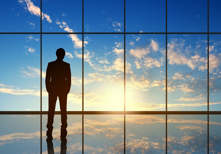Featured image: Man standing at window in front of sunrise. - 4 Key Services to Supercharge Your Glass Business