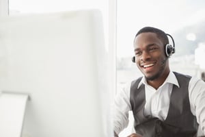 Man at computer with headphones - The Ultimate Cheat Sheet to Buying a Franchise