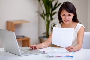 Woman on a computer with a piece of paper. - 4 Perfect Franchises for People Interested in Cleaning and Organization Businesses