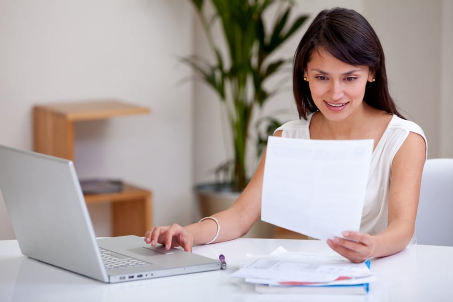 Featured image: Woman on a computer with a piece of paper. - 4 Perfect Franchises for People Interested in Cleaning and Organization Businesses