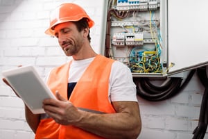 electrician using tablet near electrical box - How To Start An Electrical Business: The Electrician's Guide