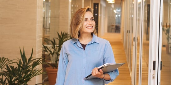 woman smiling and holding a laptop